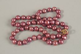 AN 18-INCH DARK PINK/PURPLE CULTURED PEARL NECKLACE with gold-plated clasp.