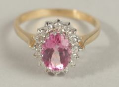 A 9CT WHITE AND YELLOW GOLD RING set with oval pink topaz surrounded by a halo of R/C diamonds.