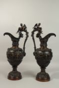 A SUPERB PAIR OF CLASSICAL BRONZE EWERS decorated with fruiting vines, cupids, rams masks and winged