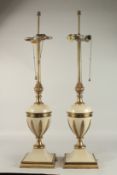 A PAIR OF EARLY 20TH CENTURY CREAM AND BRASS LAMPS with pineapples and leaves. 60cms high