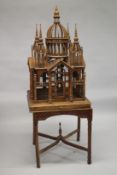 A LARGE WOODEN BIRDCAGE ON A STAND. 180cms high x 65cms square.