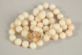 A STRING OF WHITE CORAL BEADS with white gold clasp. 52cms long.