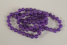 A STRING OF AMETHYST BEADS. 76cms long.