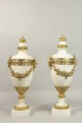 A SUPERB PAIR OF LOUIS XVI STYLE WHITE MARBLE URNS with fruit finial, garlands of flowers, on square