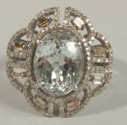 AN ORNATE DRESS RING in silver, set with an oval aquamarine surrounded by baguette and R/C