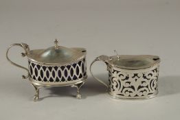 TWO PIERCED OVAL SILVER MUSTARD POTS with sapphire blue liners. Birmingham 1900 and 1922. 5ozs.