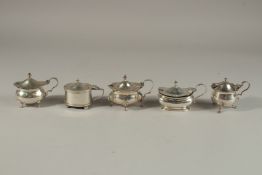FIVE VARIOUS SILVER MUSTARD POTS with sapphire blue liners. Various dates. 8ozs.