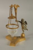 A GOOD 19TH CENTURY FRENCH ORMOLU STAND with a cupid and a swinging glass bowl. 21cms high.