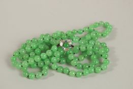 A DOUBLE STRAND OF JADE BEADS with white gold clasp. 140cms long.