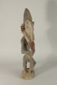 A SEPIK RIVER CARVED WOOD STANDING FIGURE, KOROGO VILLAGE, holding a paddle and painted mask.
