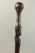 A CEREMONIAL STICK with carved head. 100cms long.