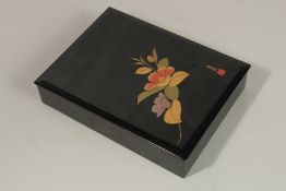 A JAPANESE BLACK LACQUER BOX AND LID with flowers. Signed. 30cms long x 22cms wide x 5cms deep.