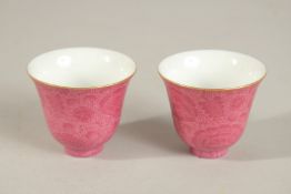 A PAIR OF CHINESE PINK GLAZED PORCELAIN CUPS, with incised flowers, base with character mark, 6.