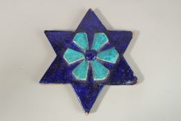 AN UNUSUAL 18TH-19TH CENTURY NORTH INDIAN MULTAN STAR TILE, with raised central flower, 42cm wide.
