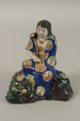 A JAPANESE KUTANI PORCELAIN FIGURE OF GUANYIN, seated upon a foo dog, 18cm high.