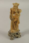 A CHINESE CARVED SOAPSTONE FIGURE OF AN IMMORTAL, mounted to a soapstone base, 20cm high.