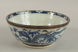 A 19TH CENTURY CHINESE CRACKLE GLAZE BLUE AND WHITE PORCELAIN DRAGON BOWL, 24cm diameter.