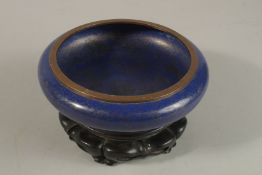 A CHINESE BLUE GROUND CLOISONNE BOWL ON HARDWOOD STAND, bowl 21cm diameter.