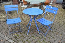 A blue painted circular bistro table with pair of matching folding chairs.