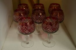 A set of eight ruby tinted cut glass wine glasses.