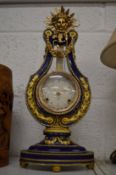 A decorative lyra shaped mantel clock.