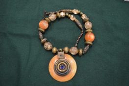 A decorative African necklace with large pendant.