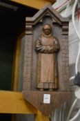A pair of carved wood plaques depicting monks stood in an archway.