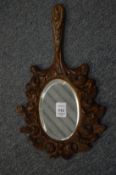 A carved oak hand mirror, dated 1946.
