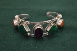 A heavy silver bangle set with coloured stones.
