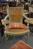 A French style pale green painted armchair with cane work back and seat.
