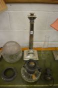 A plated corinthian column style oil lamp with cut glass reservoir and original lamp fitting