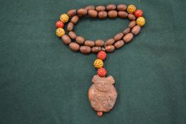 A wooden bead necklace with a pendant carved as a Buddha.