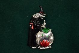 An enamel witch and potion pot brooch.