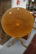 A mahogany circular tilt-top tripod table.