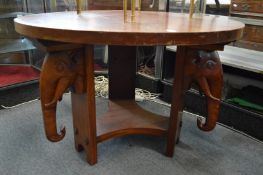 A mahogany circular coffee table with elephant head supports.