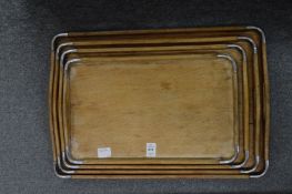 A graduated set of four oak and chrome twin handled trays.