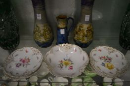 A set of four Royal Nymphenburg porcelain plates and a bowl painted with flowers.