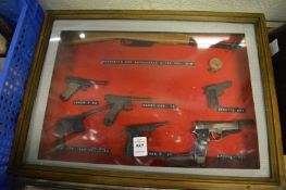 A collection of miniature pistols and rifles in a glazed case.