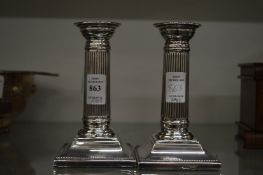A pair of silver candlesticks with square bases.