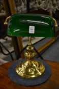 A brass desk lamp with green glass shade.