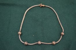 A silver necklace with ball decoration.