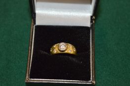 A yellow metal ring set with a central diamond with three smaller diamonds to each shoulder.