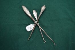 Three silver handled button hooks.
