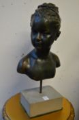 A bronze resin bust of a young girl on a stone style base.
