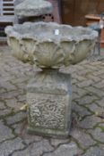 A reconstituted stone pedestal planter.