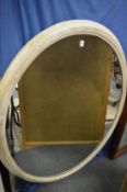 A large oval mirror with white painted pine frame.