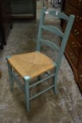 A green painted and rush seated ladder back chair.