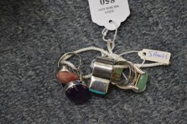 A collection of five decorative silver rings.