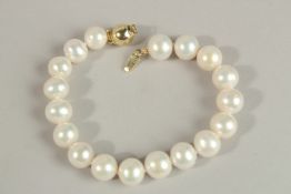 A WHITE CULTURED PEARL BRACELET with gold-plated ball clasp.