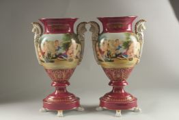 A PAIR OF SEVRES DESIGN RED GROUND TWO HANDLED VASES with classical designs. 40cms high.